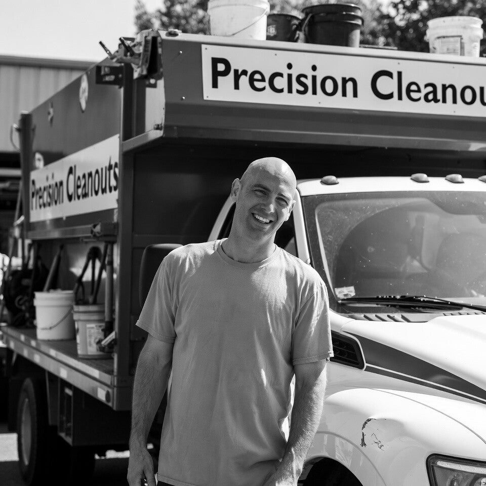 Black-and-white photo of Lonnie smiling in front of his Precision Cleanouts truck